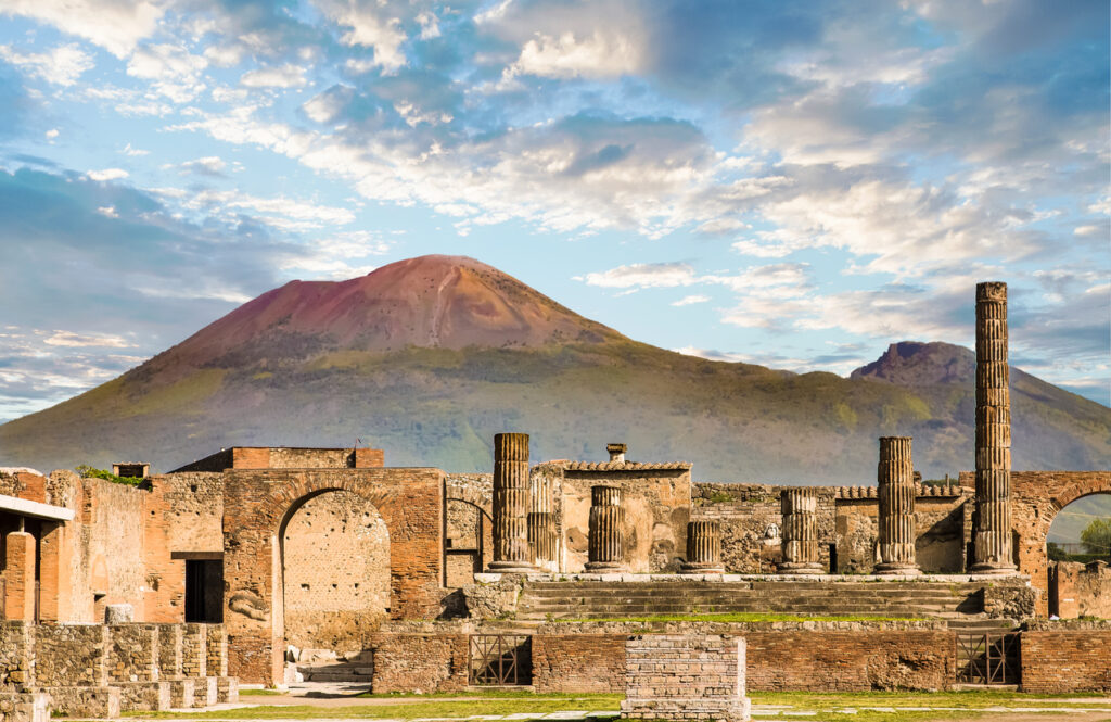 Ancient ruins of Pompeii with Mount Vesuvius in the background under a blue sky